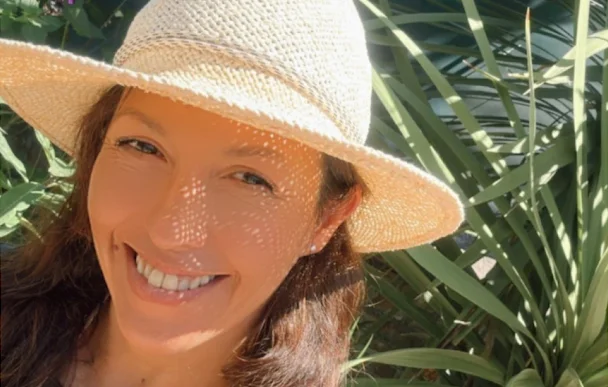 Pau, sonriendo, con sombrero de paja entre plantas